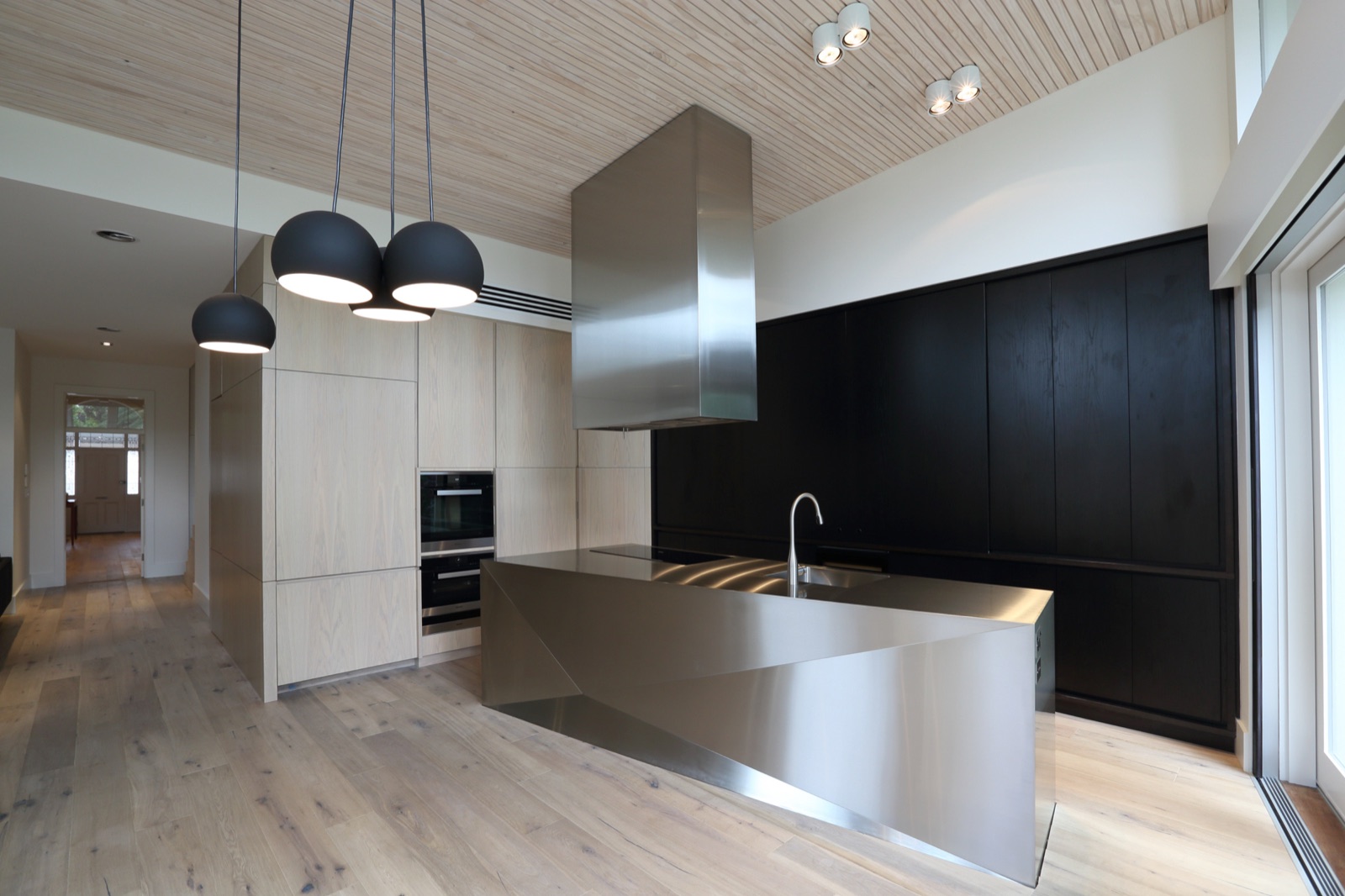 Sculpted stainless island bench under raked timber ceiling